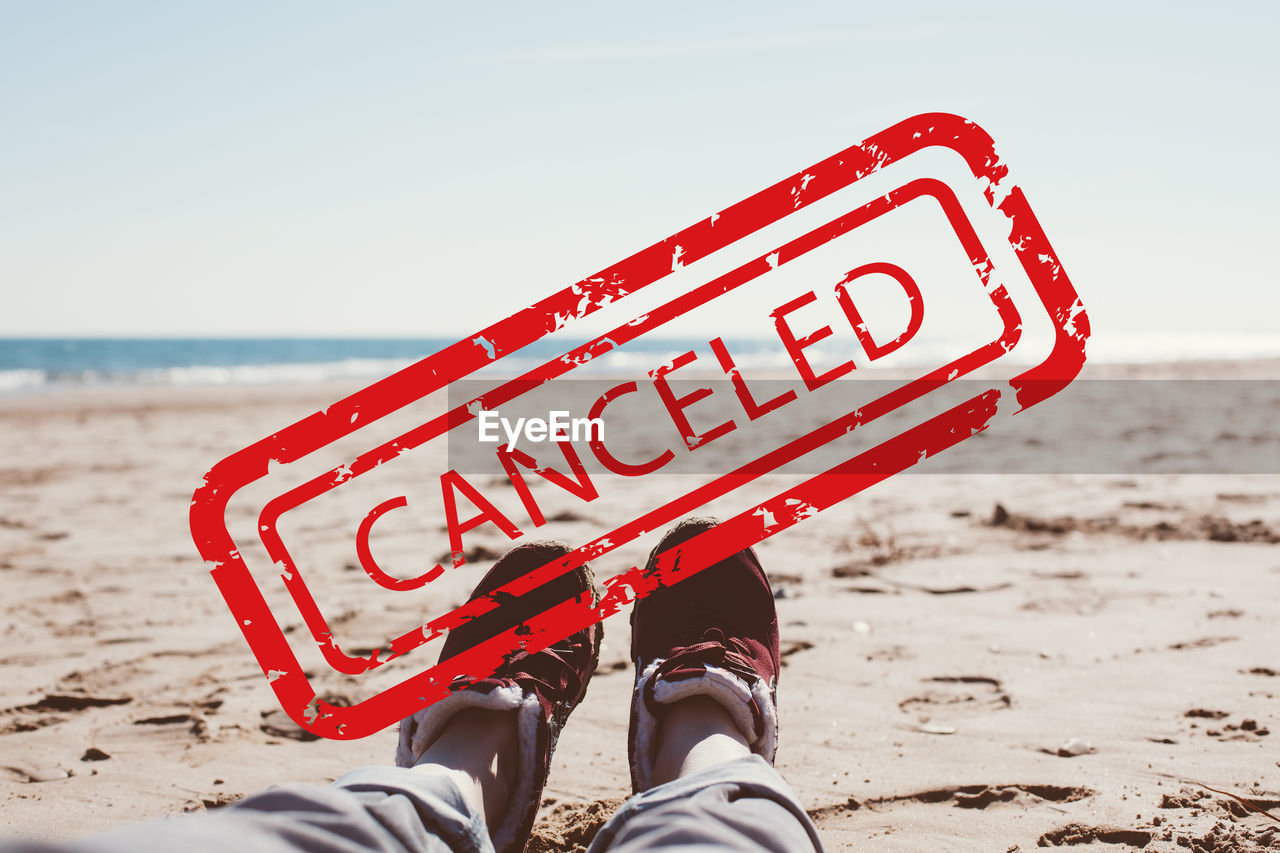 LOW SECTION OF PERSON WITH TEXT ON BEACH