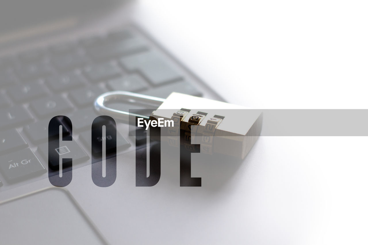 High angle view of padlock on laptop with text against white background