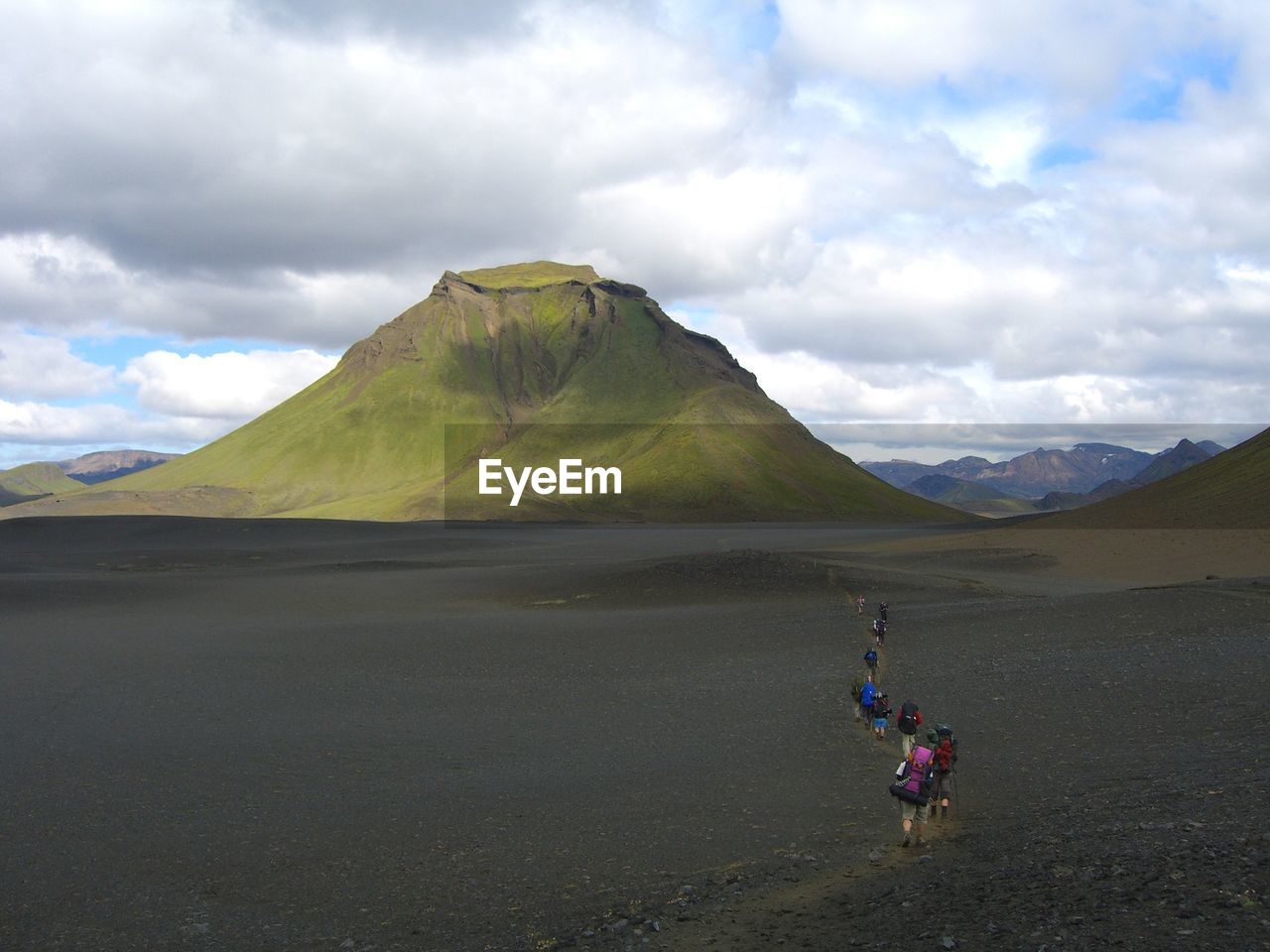 People walking on landscape against mountains