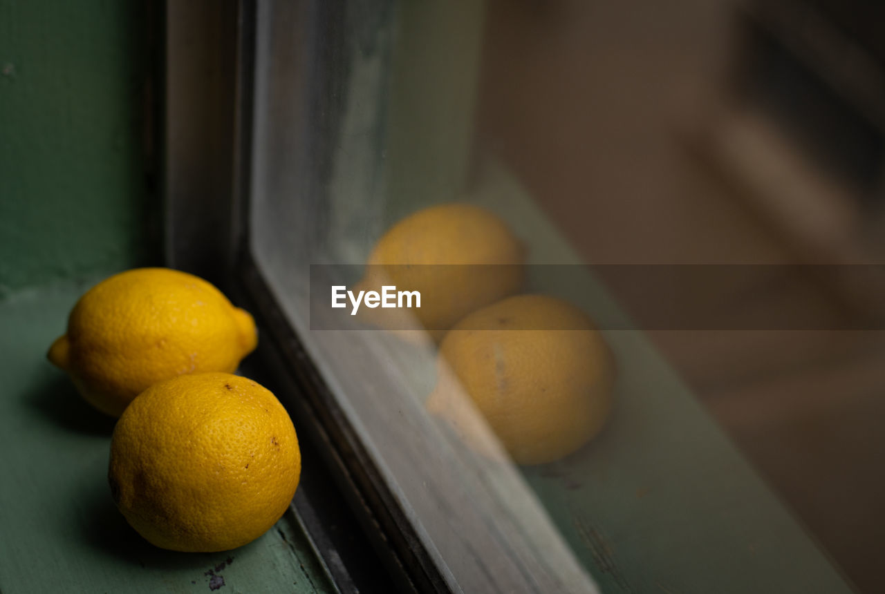 Close-up of citrus fruits on windowsill with reflection