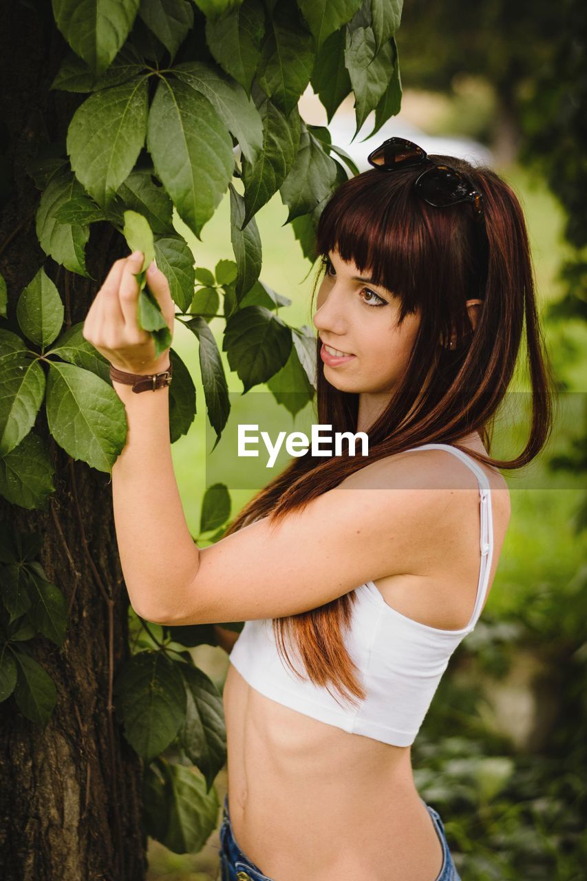 Side view of woman standing by tree