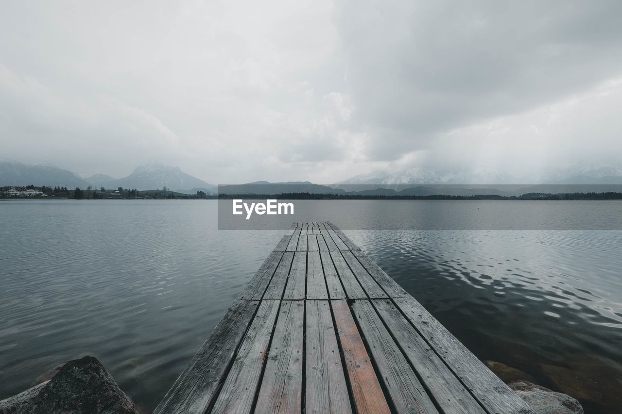 Footbridge leading into the water at lake hopfensee in the bavarian alps.