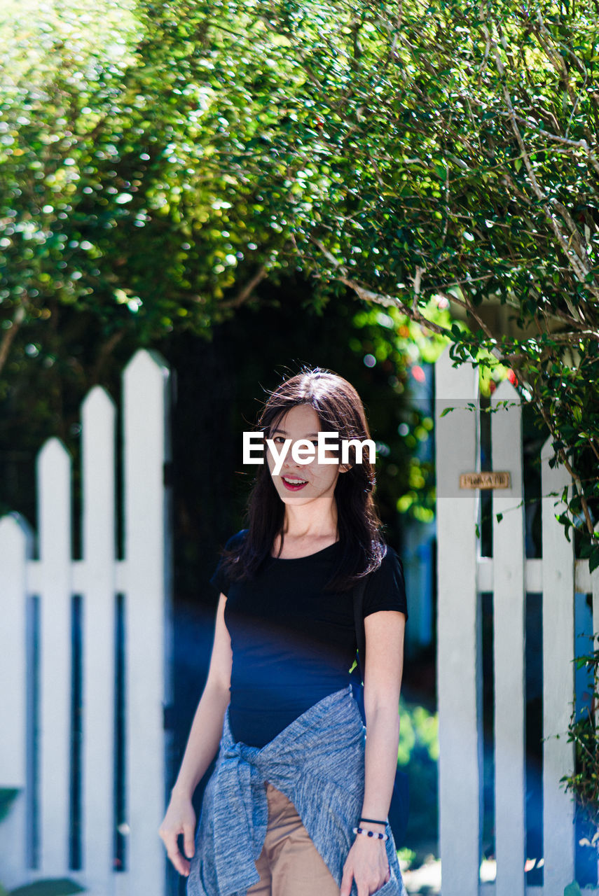 Portrait of young woman standing against plants