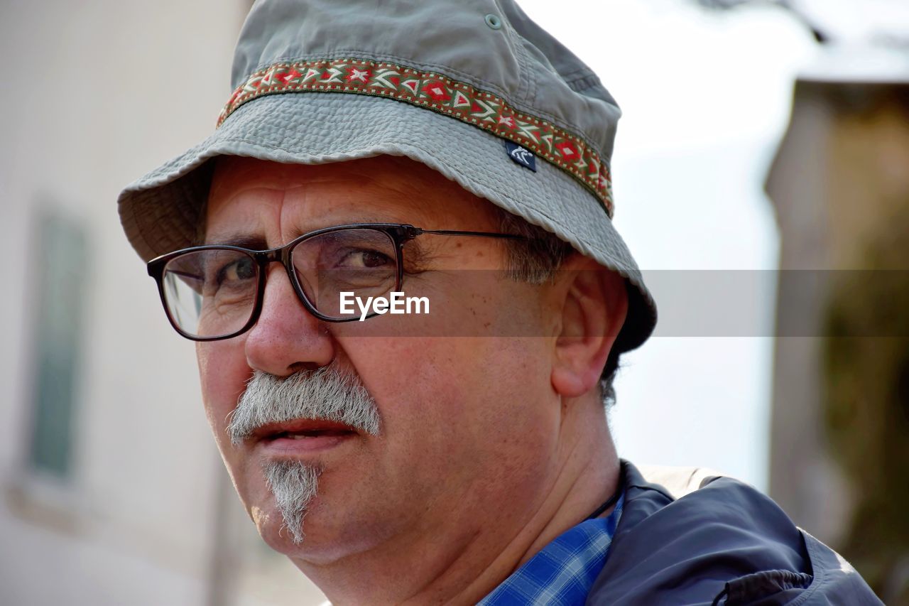 Portrait of senor man wearing hat and eyeglasses outdoors