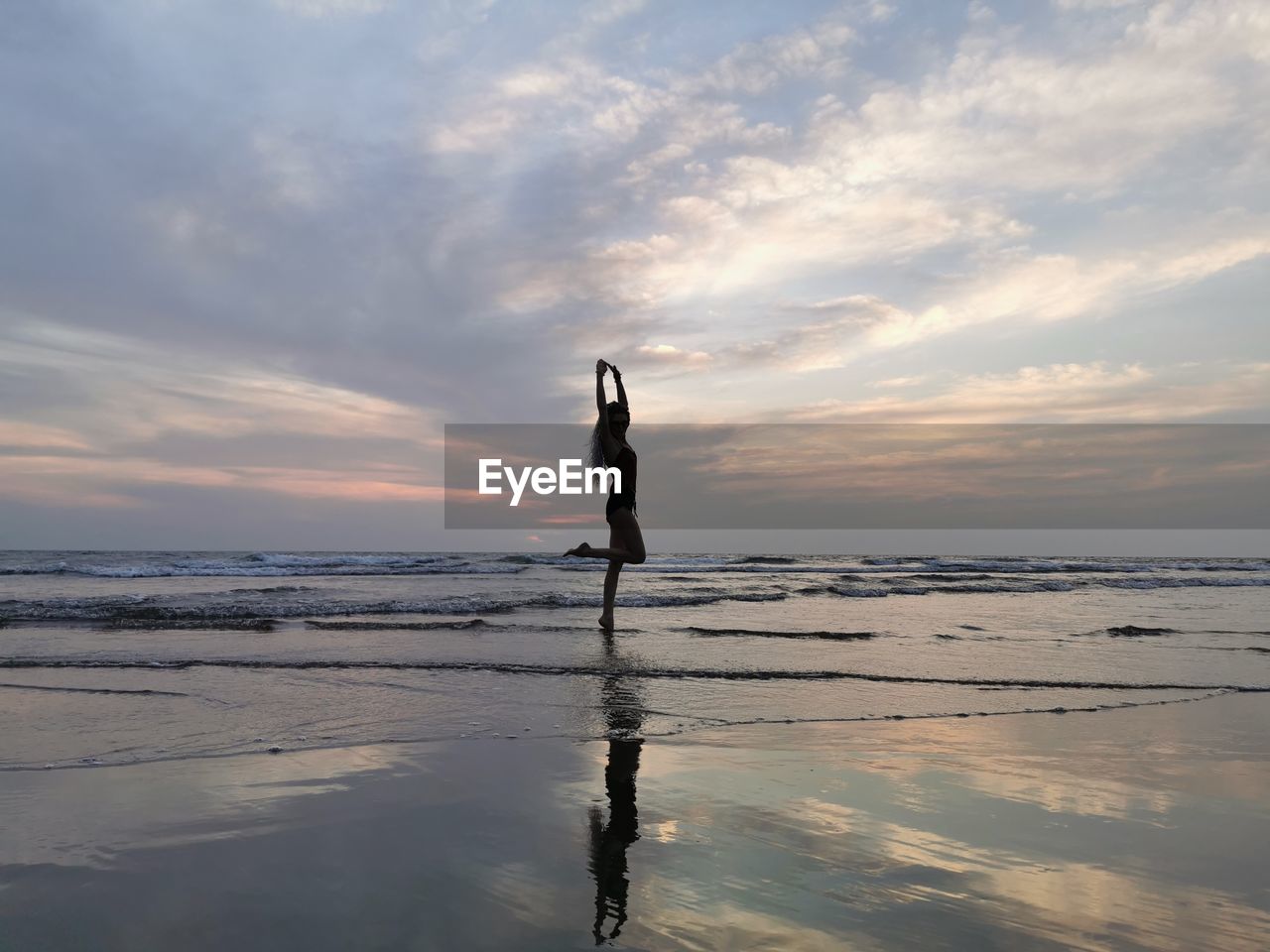 Man standing on beach against sky during sunset