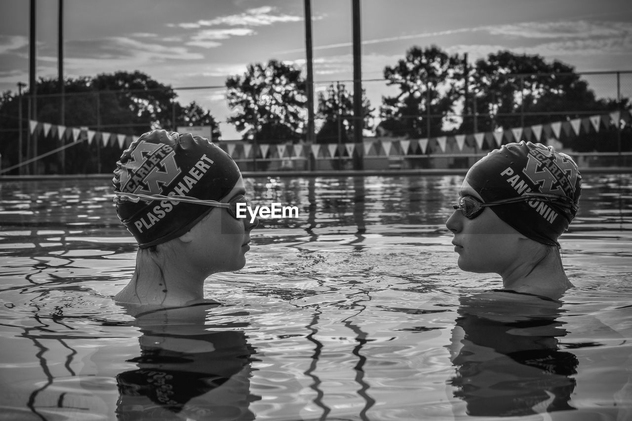 REAR VIEW OF PEOPLE AT SWIMMING POOL