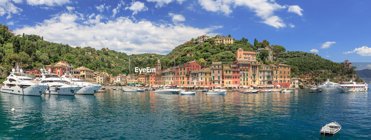 Sailboats moored on river by buildings in city against sky