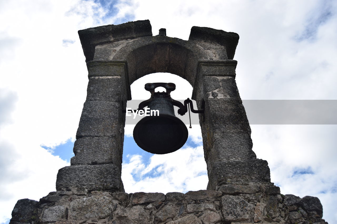 Low angle view of bell tower against clouds