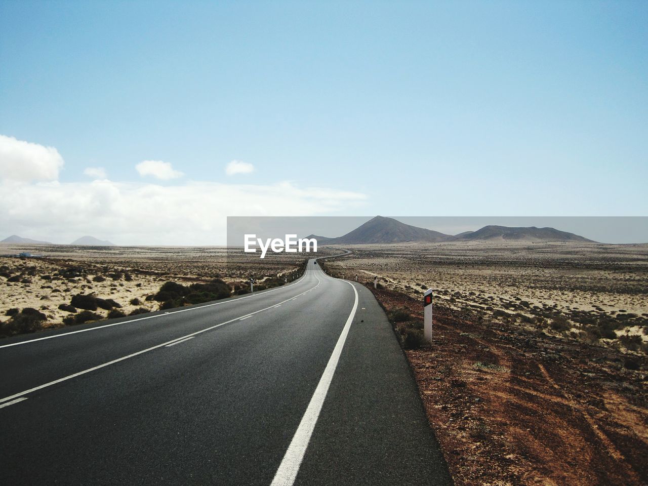 Diminishing perspective of road leading towards mountains against sky