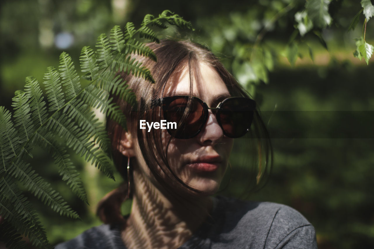 Portrait of young woman wearing sunglasses in forest