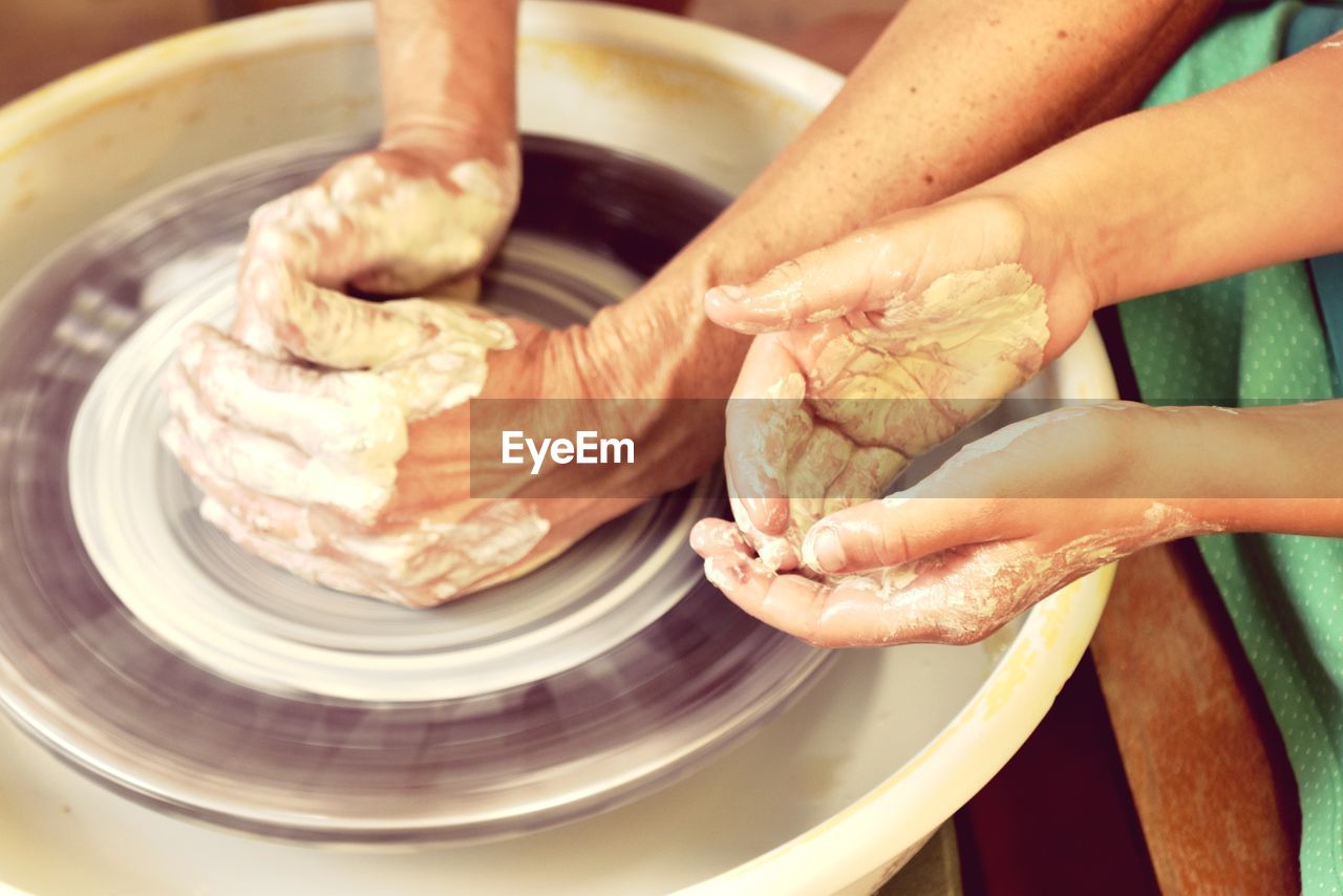 Close-up of people working on pottery wheel