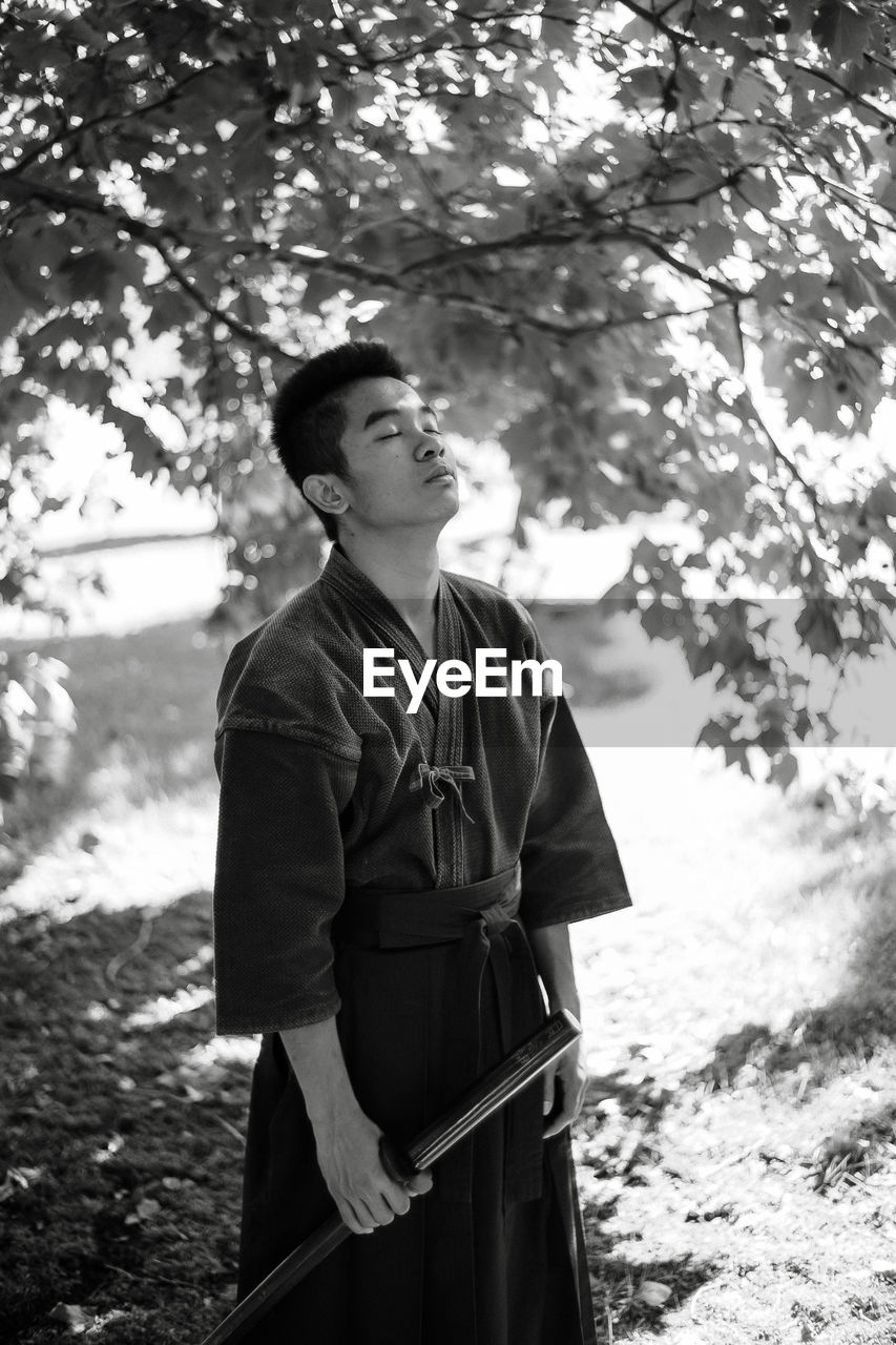 YOUNG MAN STANDING ON TREE