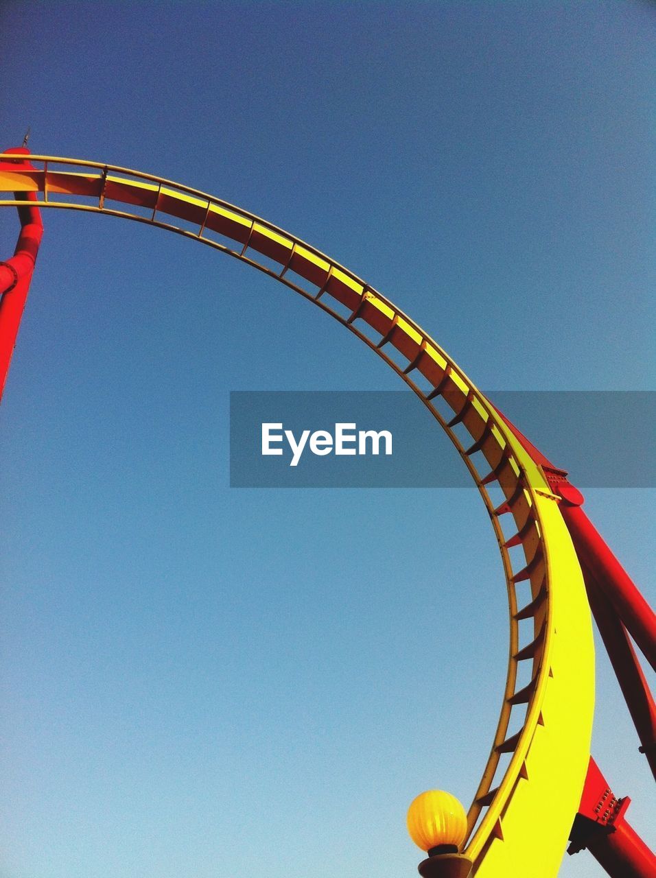 Low angle view of rollercoaster against clear blue sky