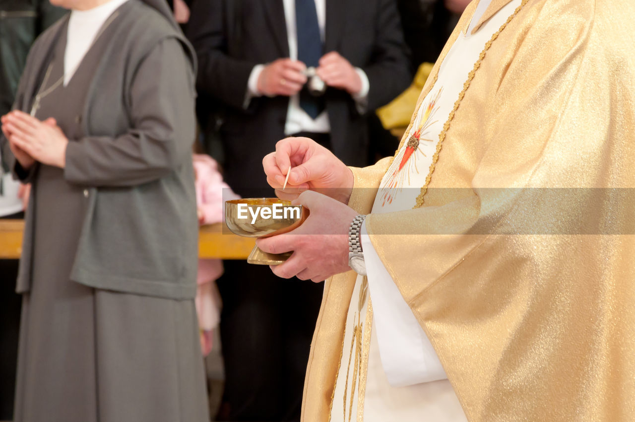 Midsection of priest holding bowl in church