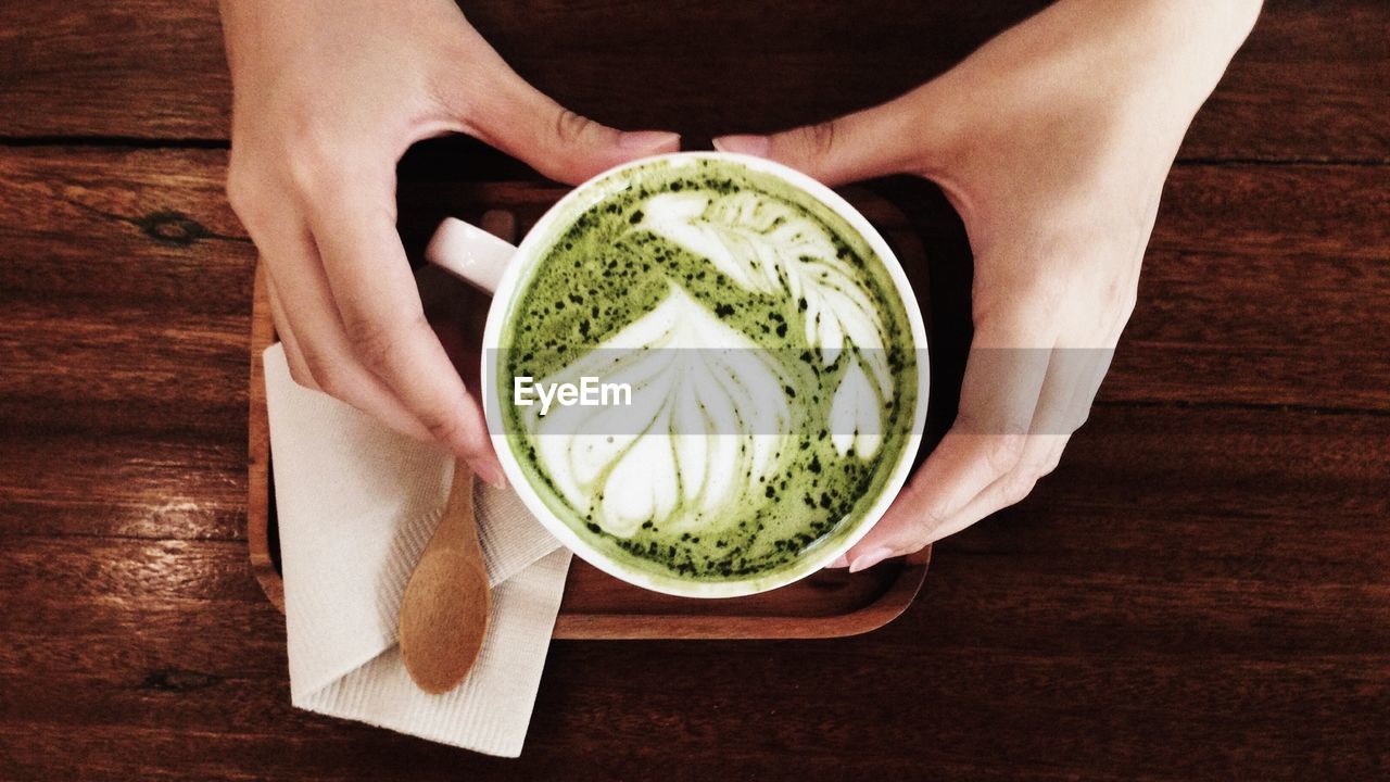 HIGH ANGLE VIEW OF MAN HOLDING TEA CUP
