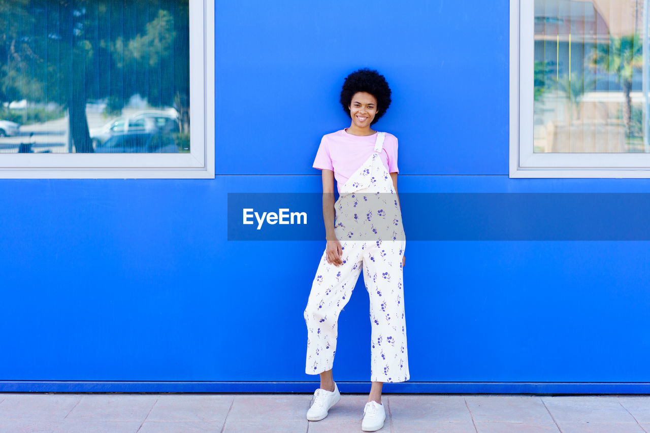 Portrait of young woman standing on footpath