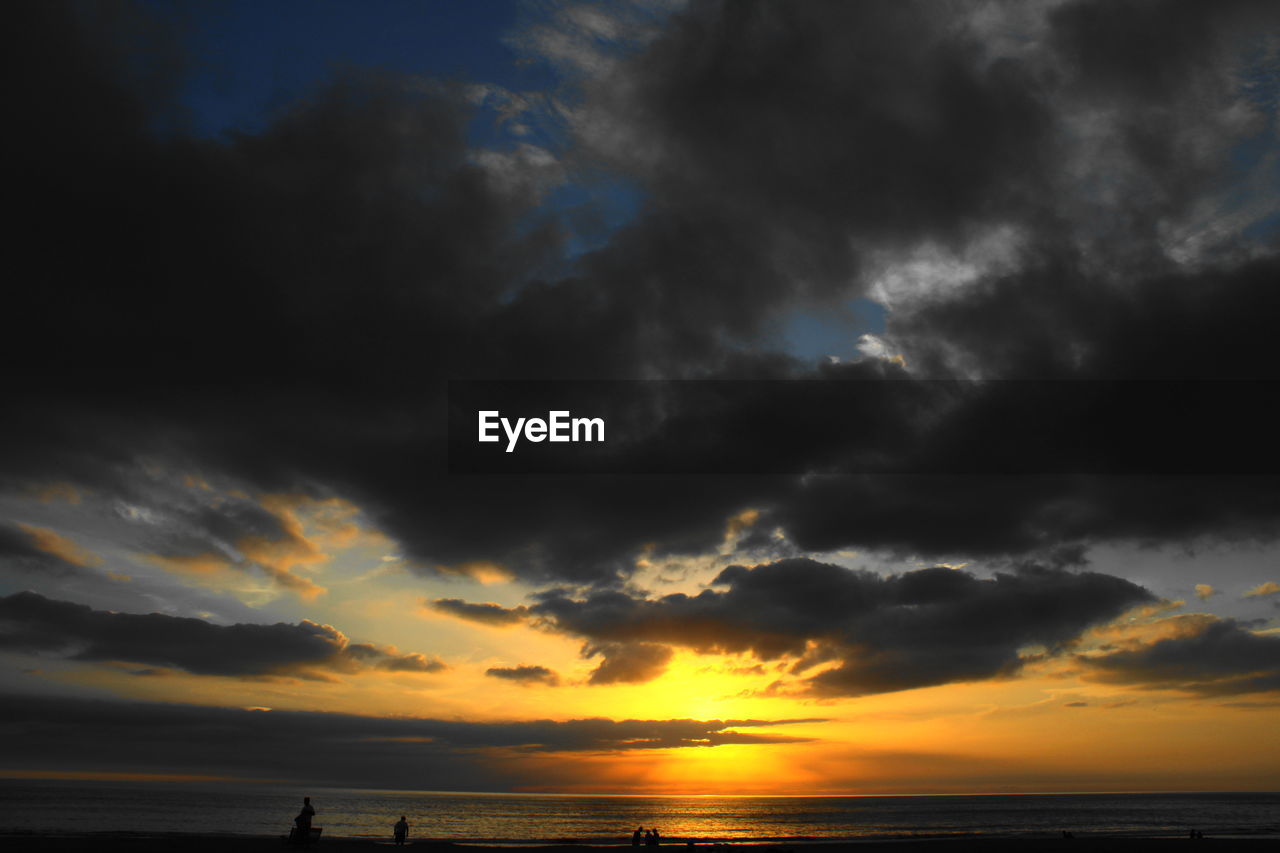 Scenic view of sea against dramatic sky during sunset