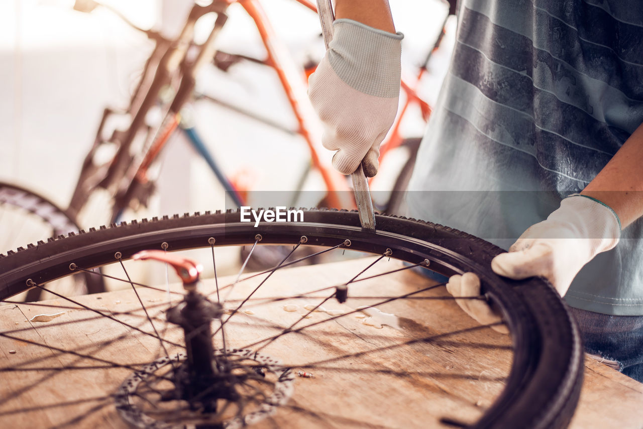 Midsection of man repairing bicycle tire