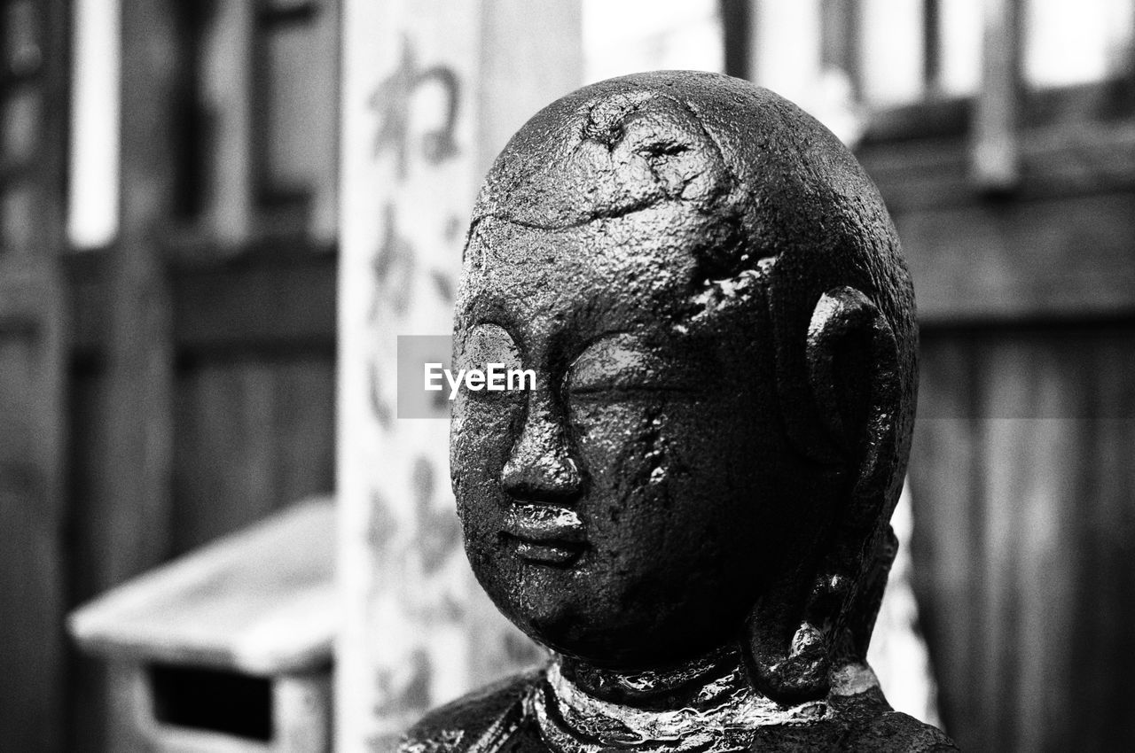 CLOSE-UP OF OLD STATUE AGAINST BLURRED BACKGROUND