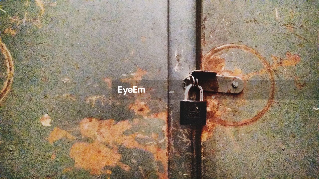 CLOSE-UP OF RUSTY PADLOCK ON DOOR