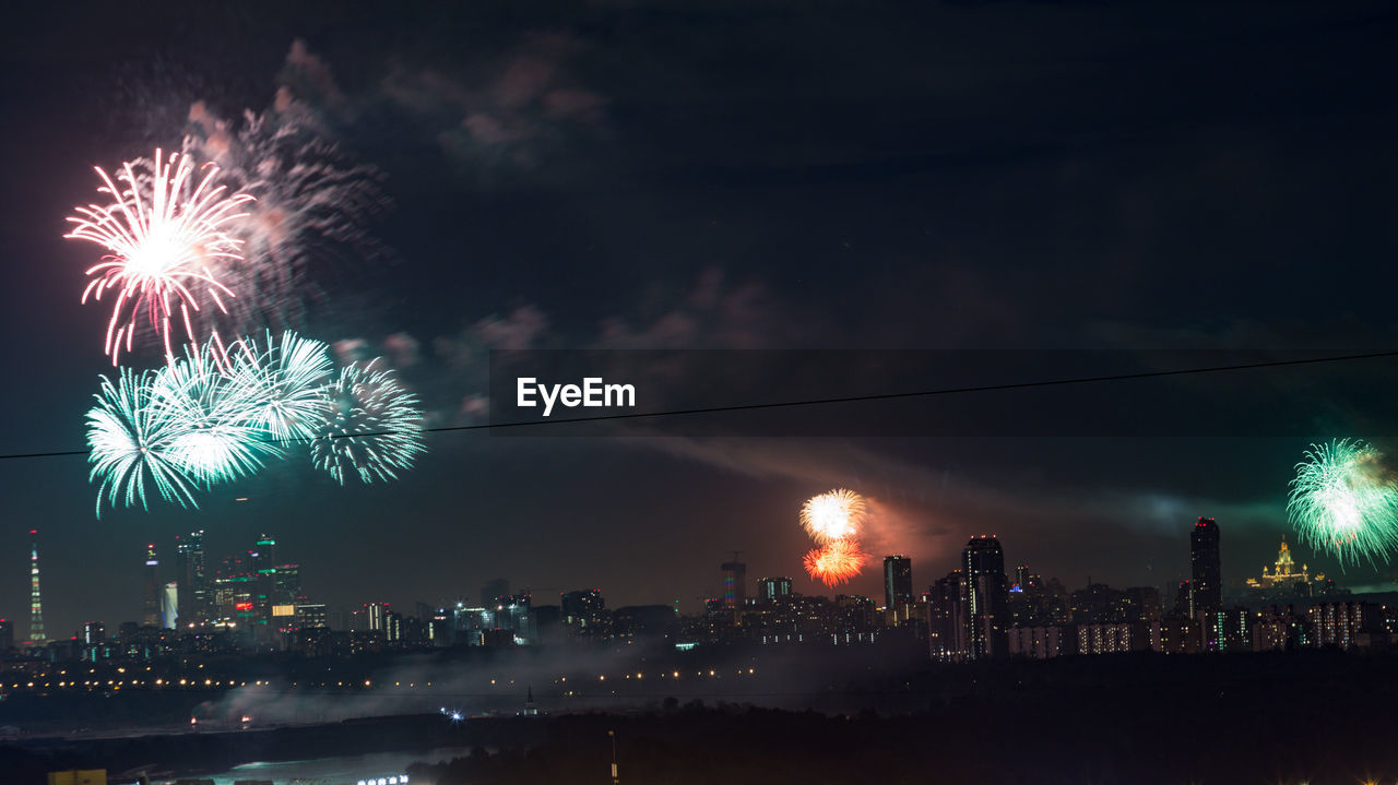 FIREWORK DISPLAY OVER CITY AGAINST SKY AT NIGHT
