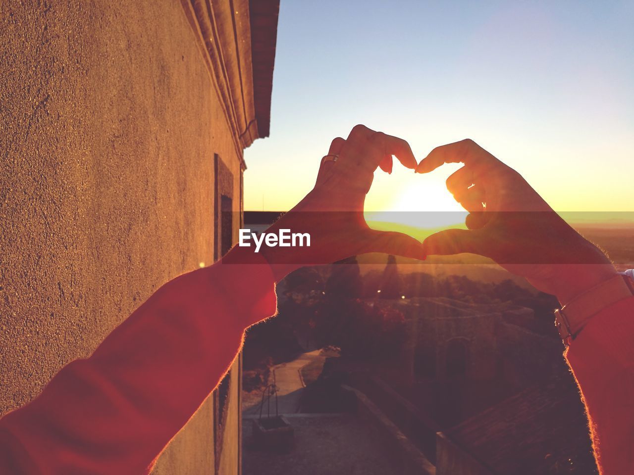 Close-up of hands holding heart shape against sky during sunset