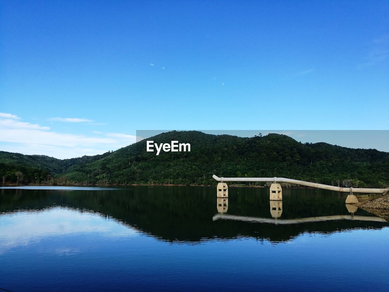 Scenic view of lake and mountains against clear blue sky