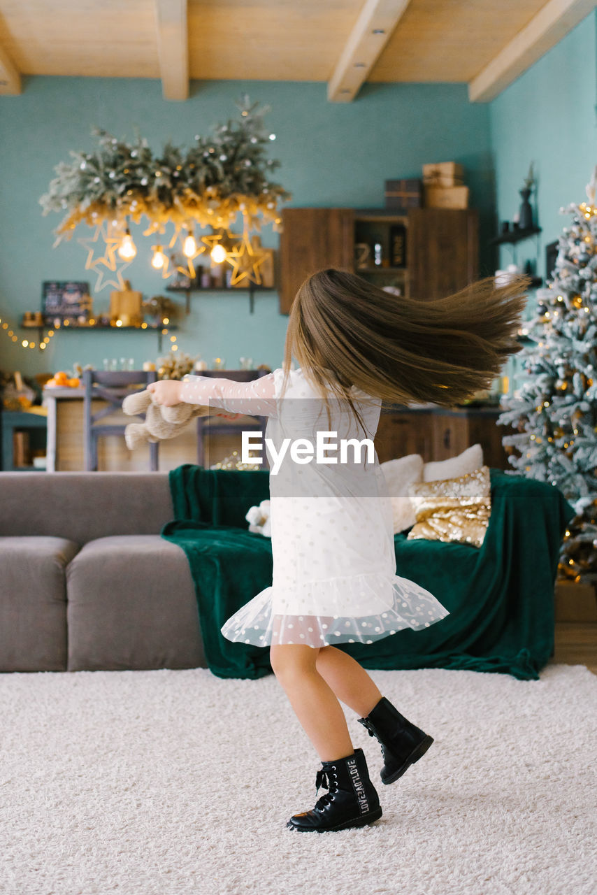 A cute girl holds a soft toy in her hands and dances with it, spinning in a room decorated 