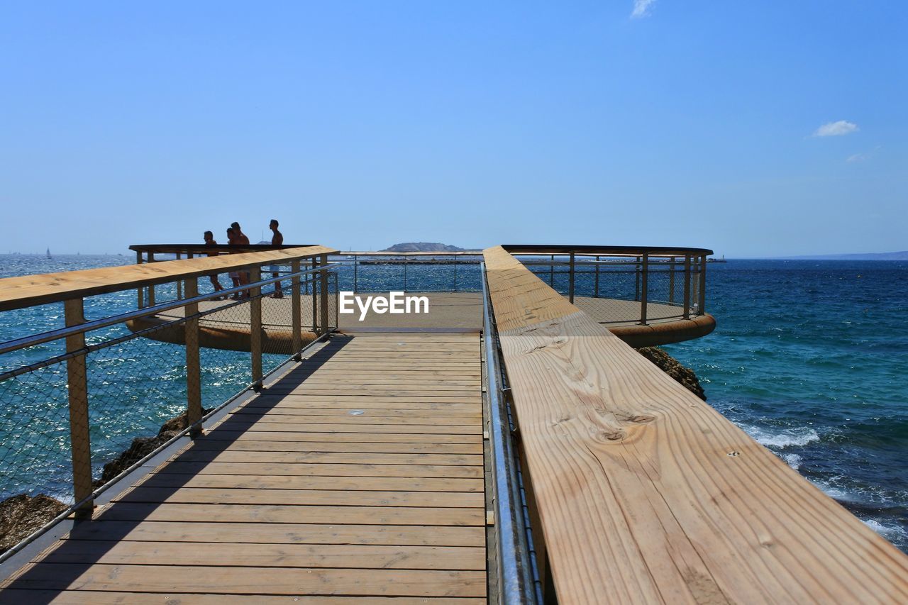 Pier over sea against clear blue sky