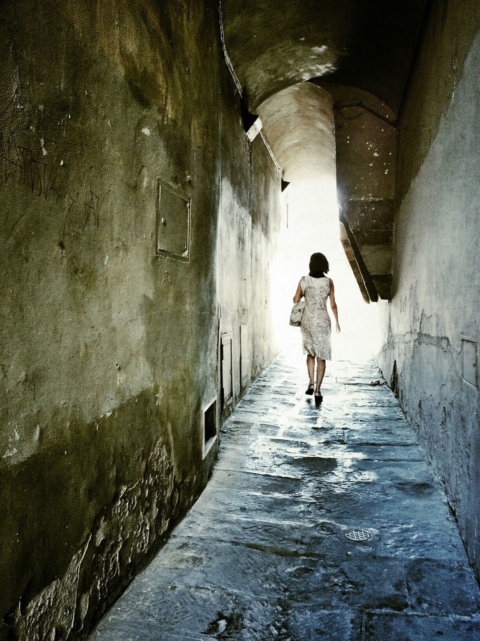 Rear view of woman walking in narrow pathway