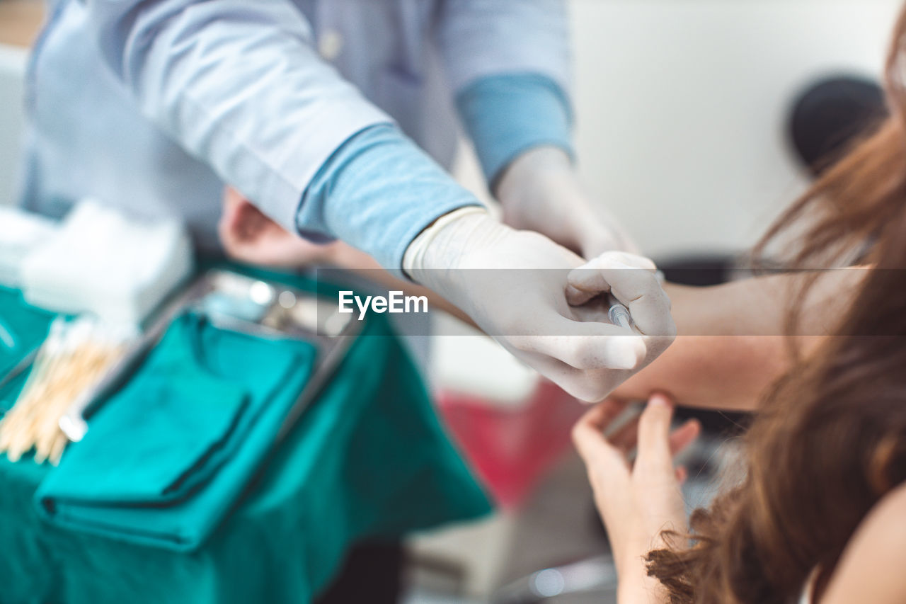 Midsection of doctor vaccinating woman