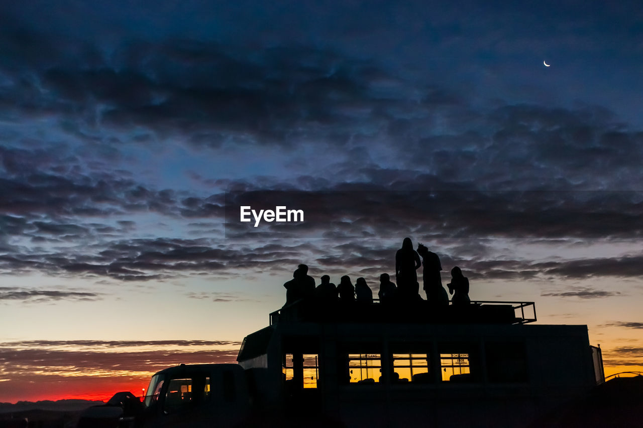 SILHOUETTE OF BUILDING AGAINST CLOUDY SKY DURING SUNSET