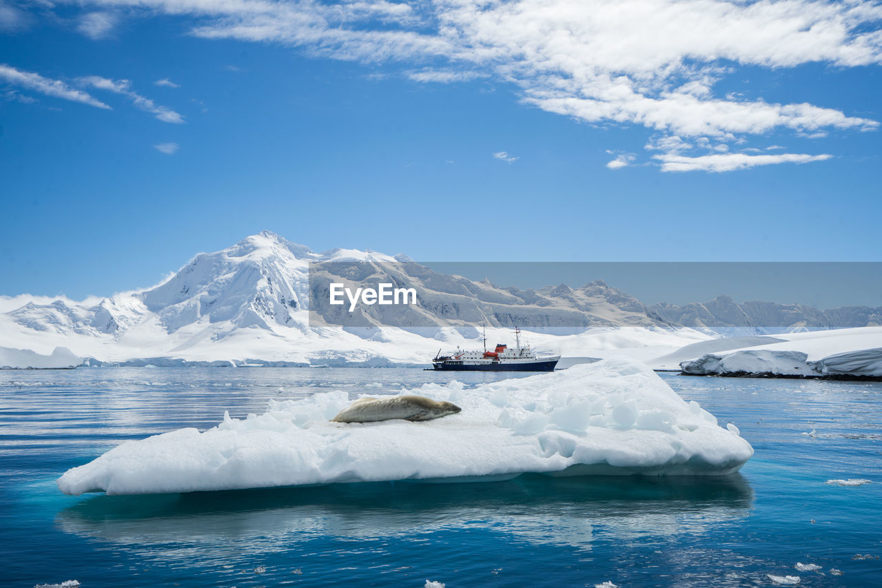 SCENIC VIEW OF SEA AGAINST SNOWCAPPED MOUNTAINS