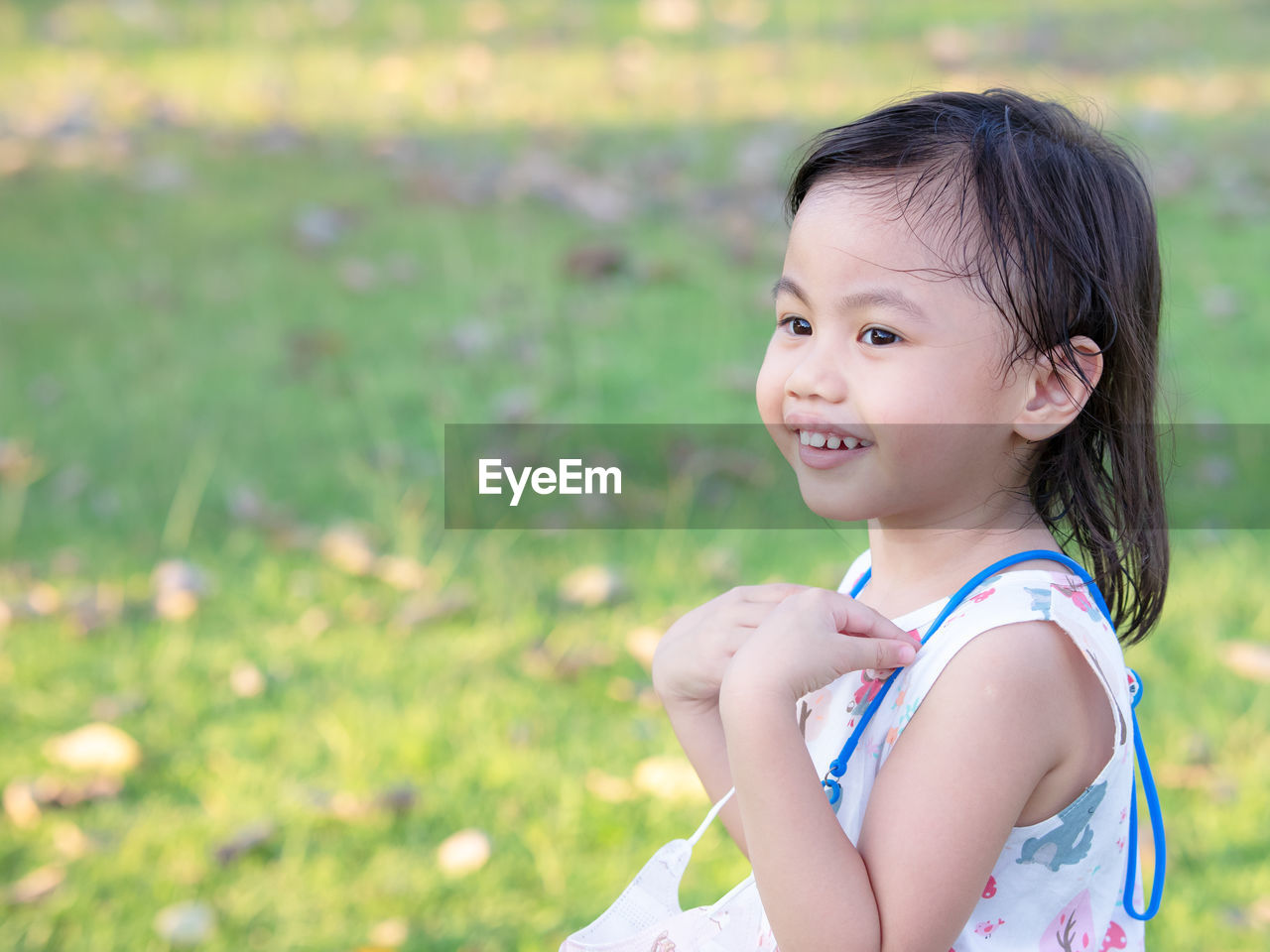 Charming 4 years old cute baby asian girl, little preschooler child smiling and looking to the left.