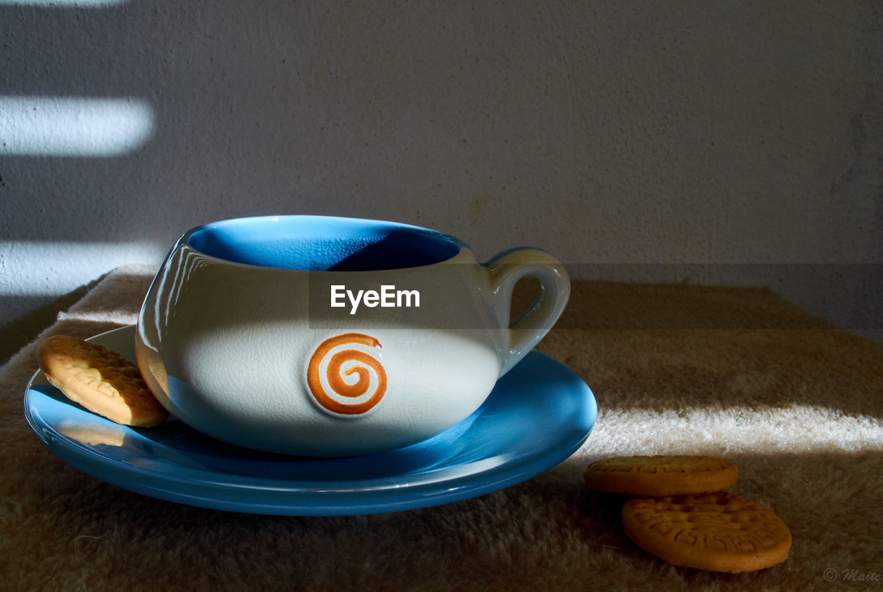 CLOSE-UP OF COFFEE CUP ON TABLE AGAINST WALL