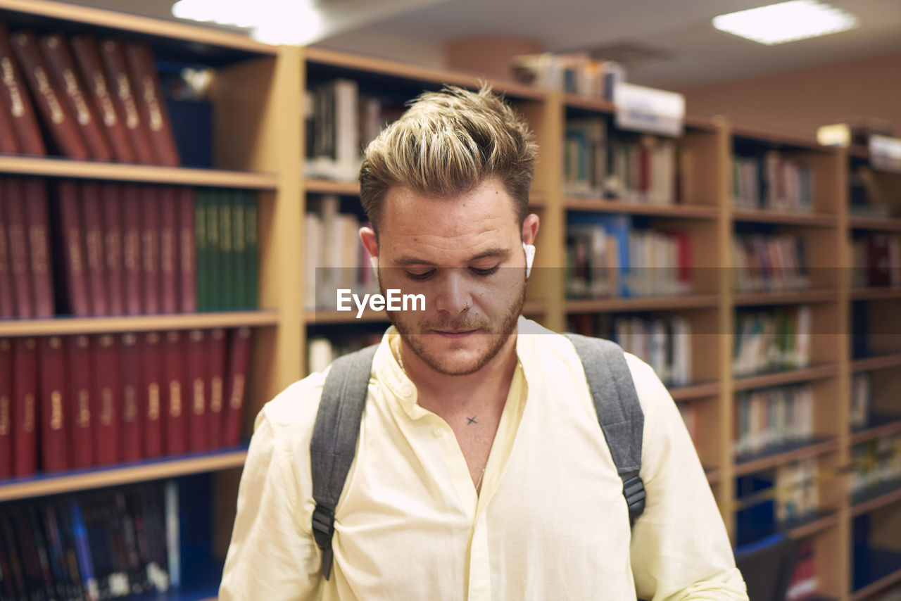 Portrait of a blond boy with headphones entering a library