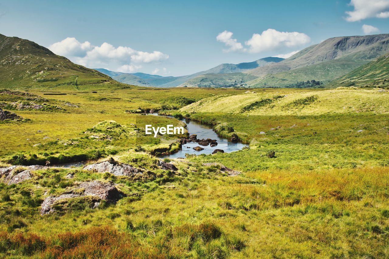 Beautiful landscape scenery of green valley with small river stream surrounded by mountains 