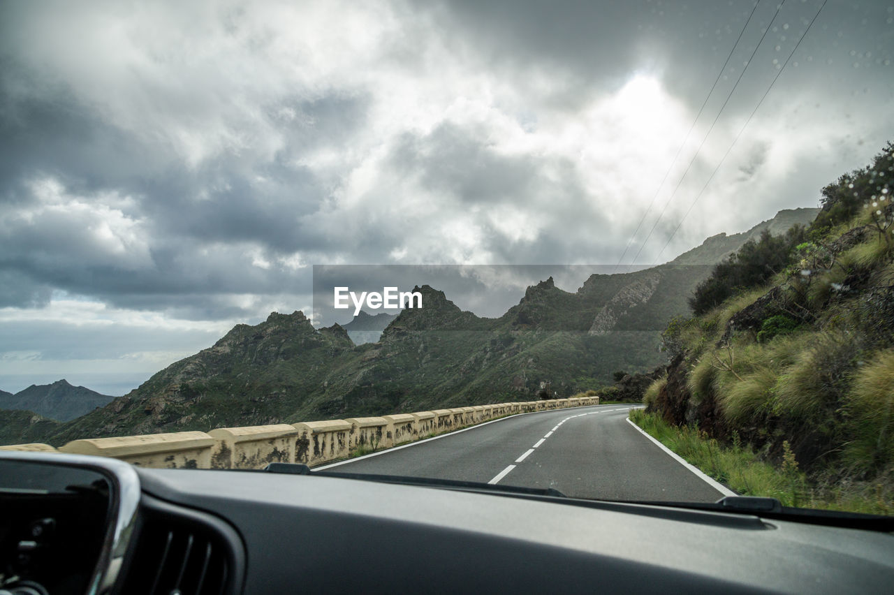 ROAD BY MOUNTAINS AGAINST SKY SEEN FROM CAR WINDSHIELD