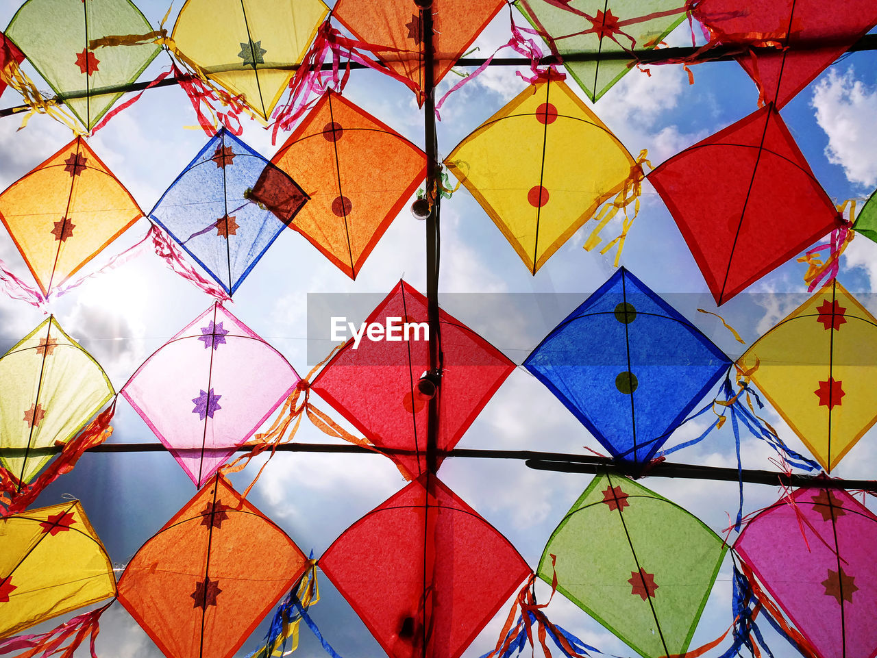 Low angle view of colorful decorative kites against cloudy sky