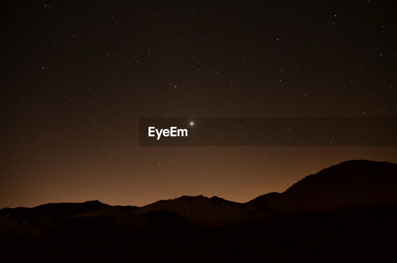 Scenic view of silhouette mountains against sky at night