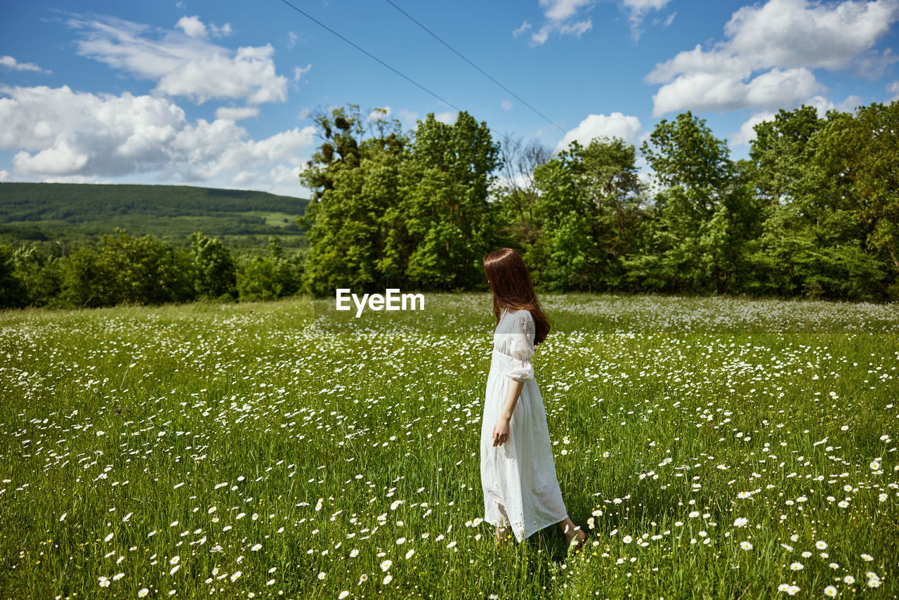 rear view of woman walking on field against sky