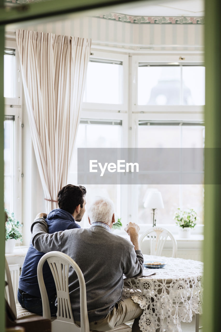 Rear view of caretaker with elderly man in nursing home