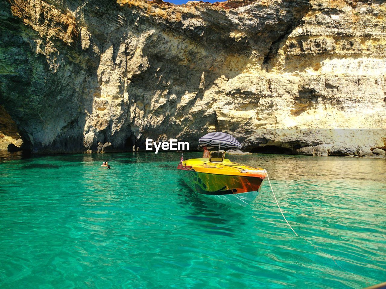 PERSON IN SEA AGAINST ROCK FORMATION