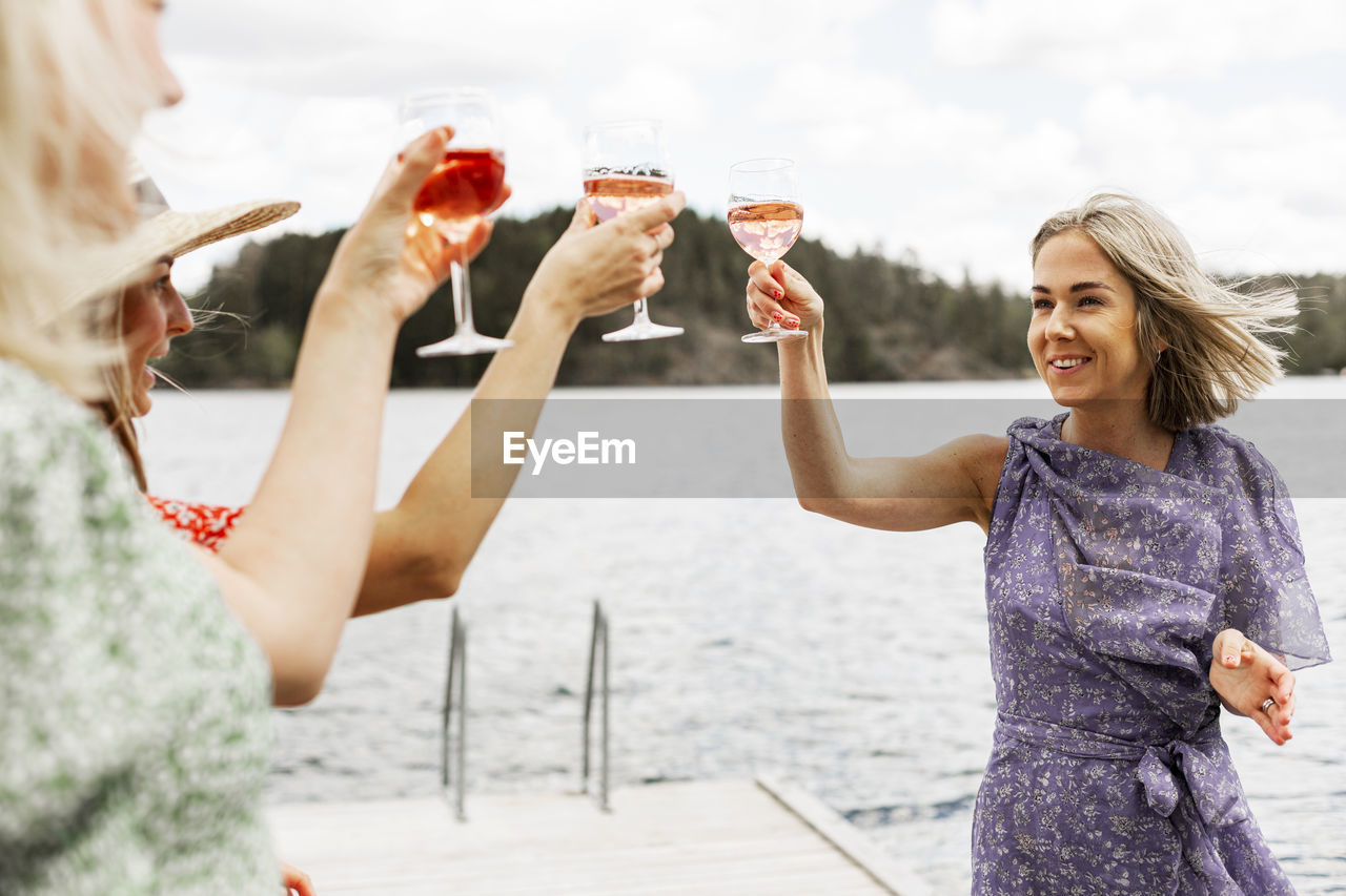 Female friends having wine on jetty