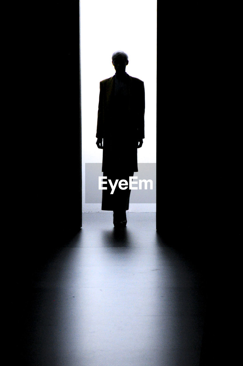 SILHOUETTE MAN STANDING IN CORRIDOR