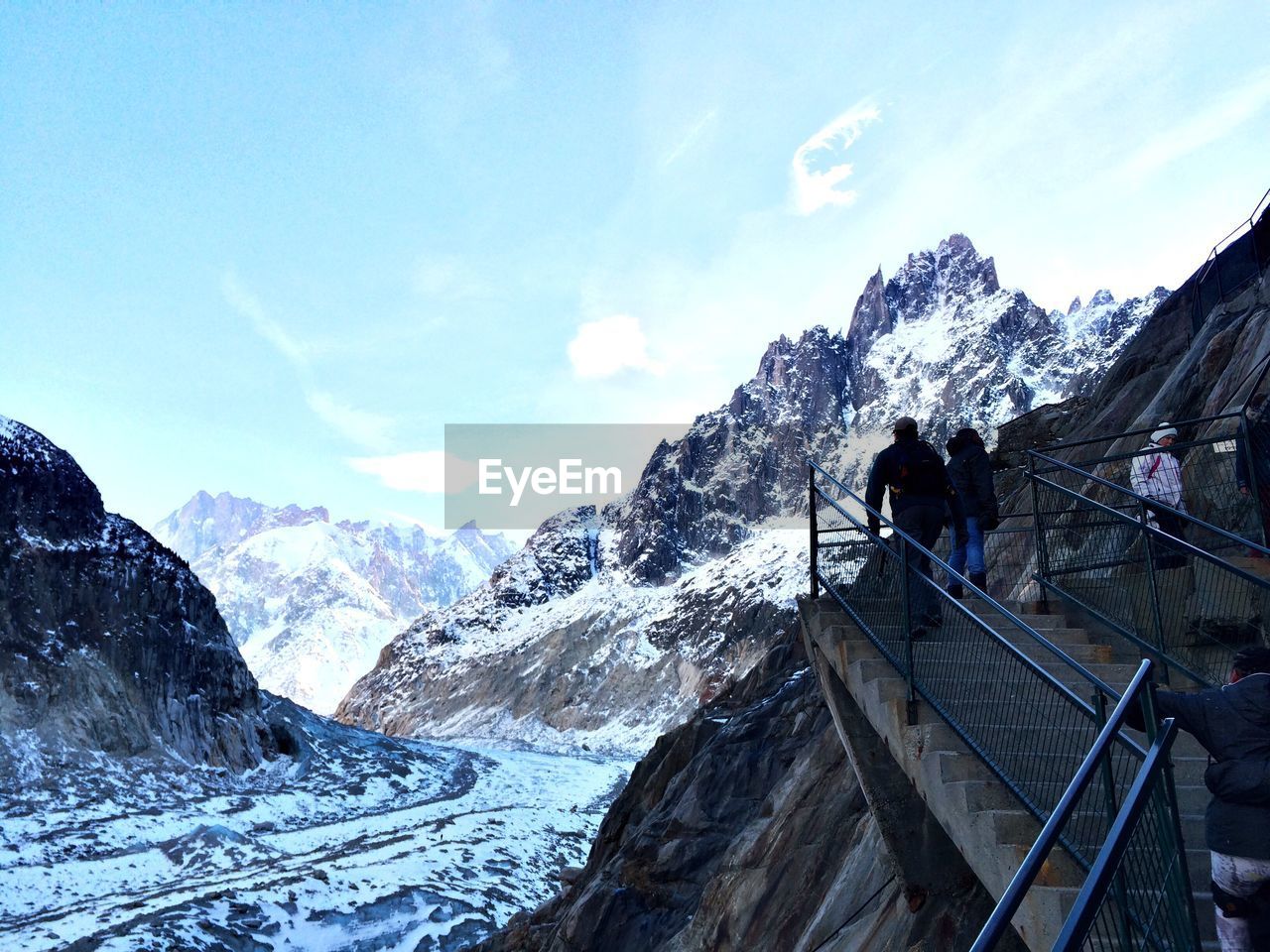 Low angle view of people on staircase by snowcapped mountain against sky