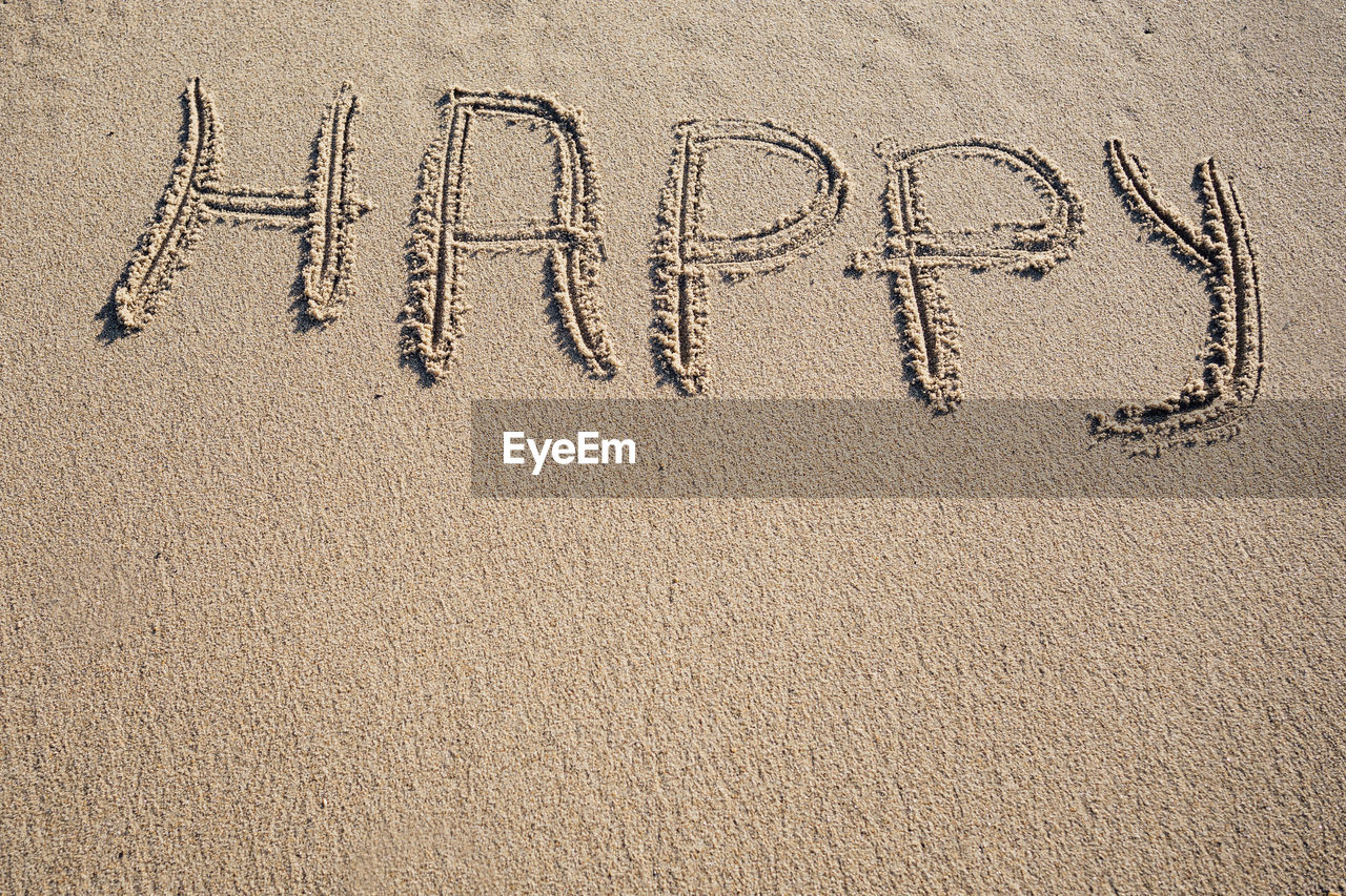 Happy word written on sand. travel summer beach vacation concept