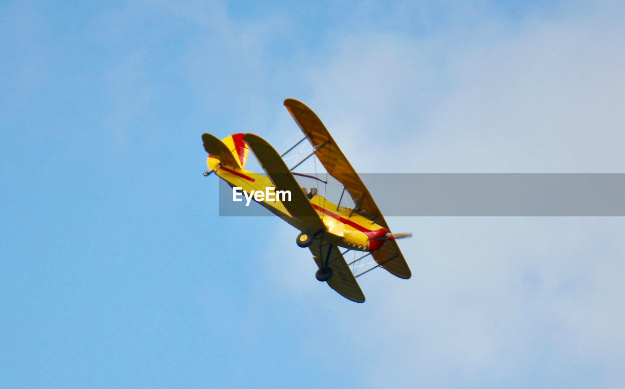 Low angle view of man flying yellow airplane in sky
