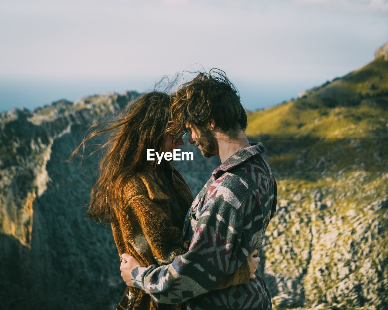 Smiling couple embracing against mountain and sky