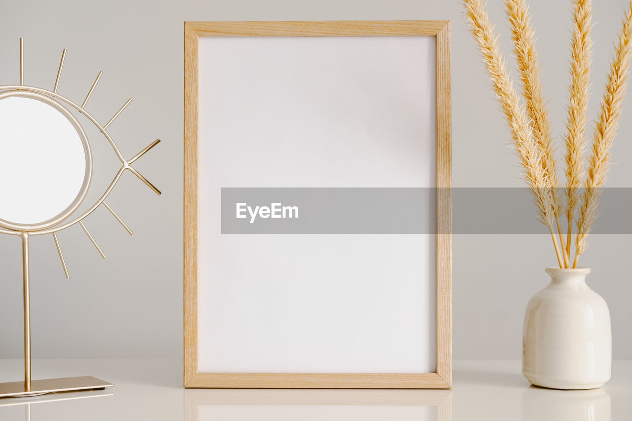 Empty wood frame on a table, blank space. photo frame surrounded by a vase with dried flowers